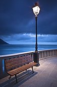 a bench and light post along the railing on the coast; camogli liguria italy