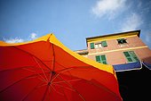 yellow and bbue patio umbrellas below a building; vernazza liguria italy