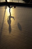a child kicks a ball and has a large shadow at sunset; camogli liguria italy