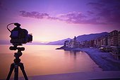 a camera on a tripod pointing towards the buildings along the coast; camogli liguria italy