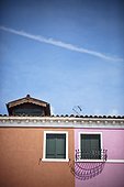 a house divided by pink and brown paint with windows; burano venezia italy