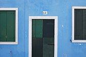 green wooden shutters and door on a blue painted wall; burano venezia italy