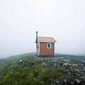 a small structure in the middle of a wide open space surrounded by fog; iceland