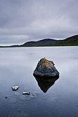 tranquil scene with rocks in the water and mountains along the shoreline; iceland
