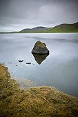 tranquil scene with rocks in the water and mountains along the shoreline; iceland