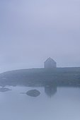 a house along the water in the fog; iceland