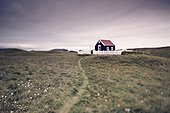a church surrounded by a white picket fence in the wide open space; papey island iceland