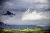the peak of a mountain seen through low lying clouds; iceland
