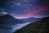 mountains along the coastline under a red sky at sunset; havelock south island new zealand
