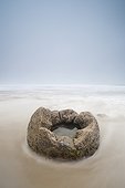 a boulder with a hole in the middle filled with water on a beach; moeraki south island new zealand