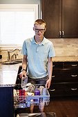 Young man unloads the dishwasher at home; Edmonton, Alberta, Canada