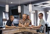 Father and mother with two sons sit at the kitchen island at home talking together; Edmonton, Alberta, Canada