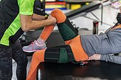 A paraplegic woman working on hip flexion while her trainer does physical queuing: Edmonton, Alberta, Canada