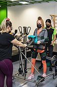 A paraplegic woman working out using an assisted walking machine with her trainers; Edmonton, Alberta, Canada