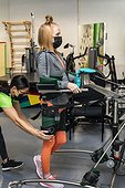 A paraplegic woman working out using an assisted walking machine with her trainers; Edmonton, Alberta, Canada
