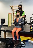 A paraplegic woman working out on a rowing machine with her trainer; Edmonton, Alberta, Canada