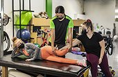 A paraplegic woman working on hip flexion while her trainer does physical queuing: Edmonton, Alberta, Canada