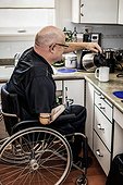 Man with double limb amputations pouring coffee in the kitchen at home; St. Albert, Alberta, Canada