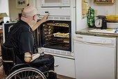 Man with double limb amputations using the oven in the kitchen at home; St. Albert, Alberta, Canada