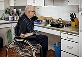 Man with double limb amputations cooking on the stovetop in the kitchen at home; St. Albert, Alberta, Canada