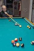 Man with double limb amputations playing a game of pool at home; St. Albert, Alberta, Canada