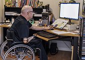 Man with double limb amputations working remotely from home on a computer; St. Albert, Alberta, Canada