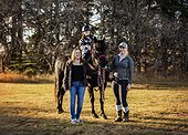 A young girl with Cerebral Palsy posing with her Mom, her trainer and a horse during a Hippotherapy session after a trail ride; Westlock, Alberta, Canada