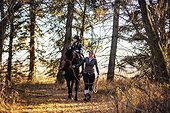 A young girl with Cerebral Palsy and her trainer working with a horse on a trail ride during a Hippotherapy session; Westlock, Alberta, Canada