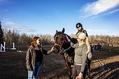 A young girl with Cerebral Palsy, her Mom and her trainer working with a horse during a Hippotherapy session; Westlock, Alberta, Canada
