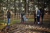 A young girl with Cerebral Palsy finishes up her Hippotherapy session with her Mom and her trainer who is leading the horse; Westlock, Alberta, Canada