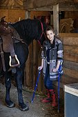 A young girl with Cerebral Palsy with a horse in a barn during a Hippotherapy session; Westlock, Alberta, Canada