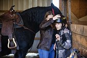 A young girl with Cerebral Palsy and her mom getting ready for a Hippotherapy session with the horse; Westlock, Alberta, Canada