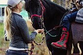 A young girl with Cerebral Palsy and her trainer stop to get a treat of apples for a horse during a Hippotherapy session; Westlock, Alberta, Canada
