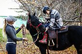 A young girl with Cerebral Palsy and her trainer stop to get a treat of apples for a horse during a Hippotherapy session; Westlock, Alberta, Canada