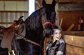 A young girl with Cerebral Palsy with a horse in a barn during a Hippotherapy session; Westlock, Alberta, Canada