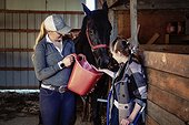 A young paraplegic girl feed a horse with her trainer during a Hippostherapy session; Westlock, Alberta, Canada