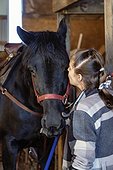 A young girl with Cerebral Palsy kissing a horse in a barn during a Hippotherapy session; Westlock, Alberta, Canada