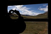 Silhouette of a female tourist photographing Mt. McKinley from the inside of a tour bus, Interior Alaska, Summer