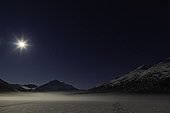 A full moon illuminates Bold Peak and ground fog on frozen Eklutna Lake in Chugach State Park in Southcentral Alaska, Winter