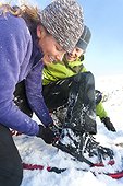 Woman helps a man adjust his snowshoe, Park City, Utah, Winter