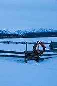 Lighted Christmas wreath on split rail fence at a rural ranch in Stanley, Idaho, Winter