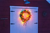 Lighted Christmas wreath on the door of a red barn at a rural ranch in Stanley, Idaho, Winter