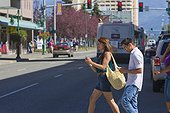 Young adult couple looking at smart phones as they cross a downtown street, Anchorage, Southcentral Alaska, Summer