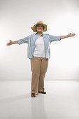 Caucasian middle aged woman wearing straw hat holding arms outstretched.