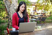 Young Woman Using Laptop And Drinking Coffee In Garden