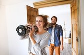 Young Couple Moving In New House, Carrying A Carpet