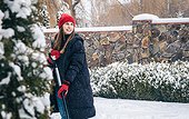 Young Woman Cleans Snow In The Yard In Snowy Weather