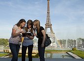 France, Paris, Three young women using tablet in front of Eiffel Tower