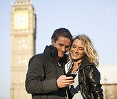 UK, London, Young couple looking at mobile, Big Ben in background