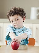 USA, Utah, Boy (6-7) sitting at kitchen table, holding red apple